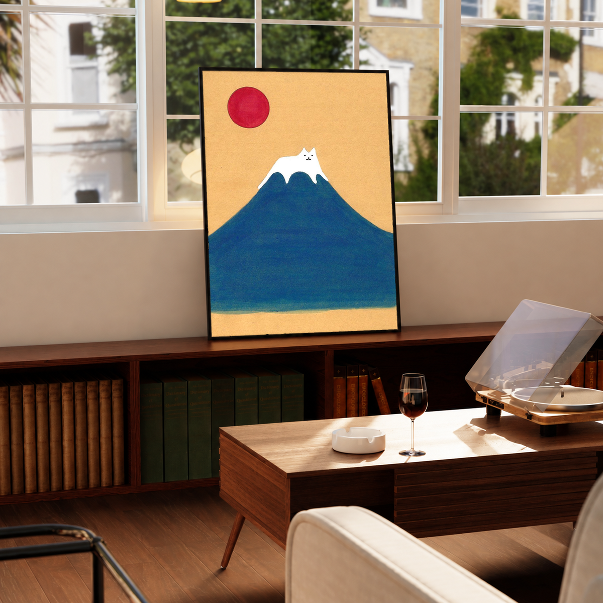 Black-framed wall art print with blue mountain, red sun, and white cat