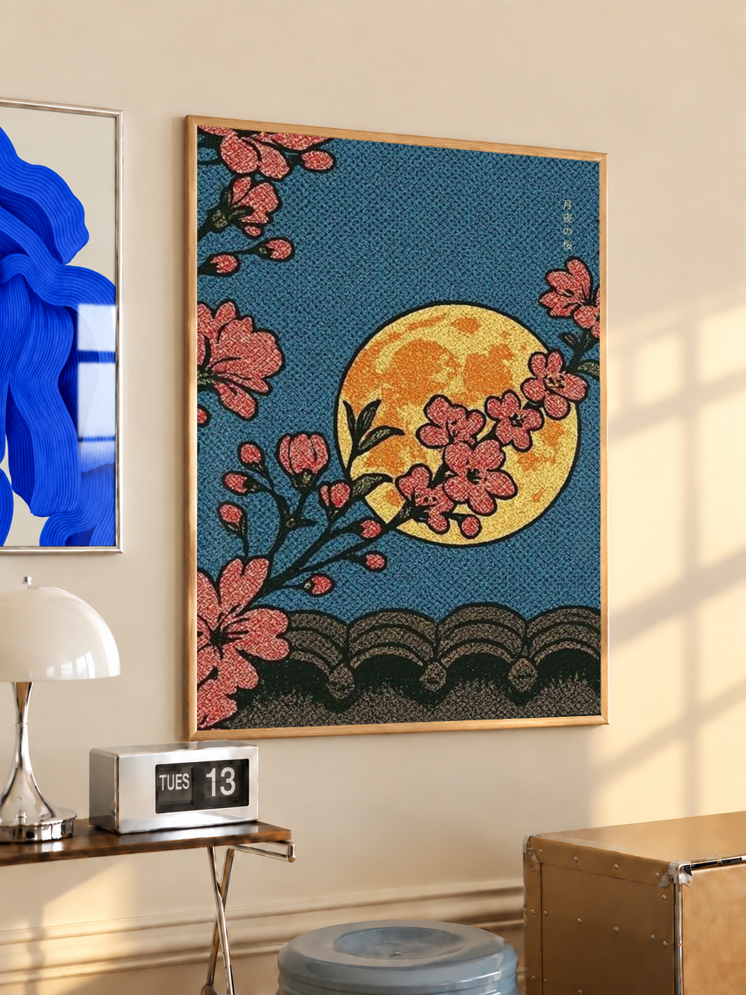 Cherry blossoms, yellow moon and patterned waves in an oak frame on a warm cream wall above a small table and dome lamp