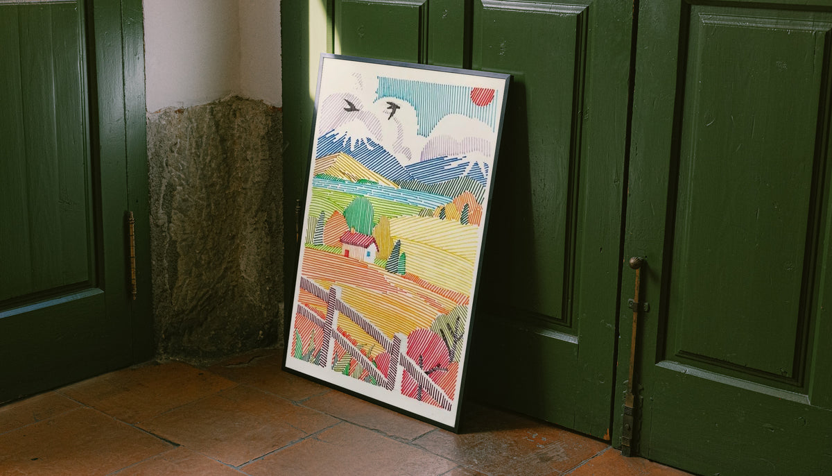 A red-roof farmhouse among colorful striped fields, mountains, birds and a foreground fence leaning on the floor against dark green wall panelling