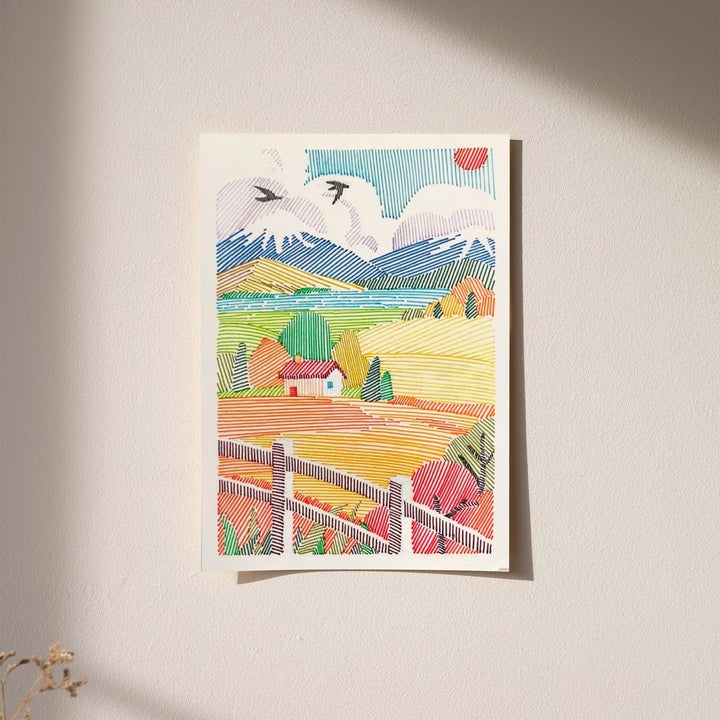 A red-roof farmhouse among colorful striped fields, mountains, birds and a foreground fence displayed without a visible frame on a softly lit pale wall