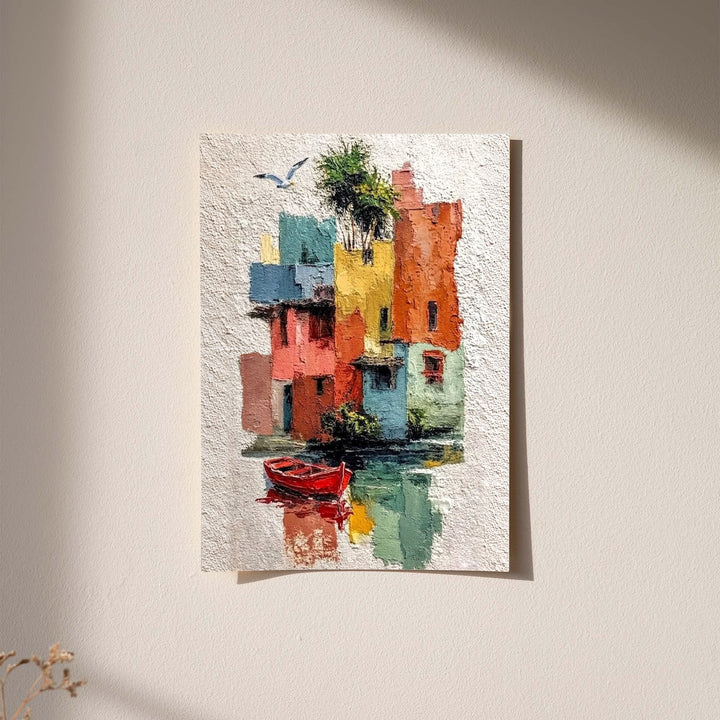 Colorful waterfront houses reflected in green water beside a small red boat displayed without a visible frame on a softly lit pale wall