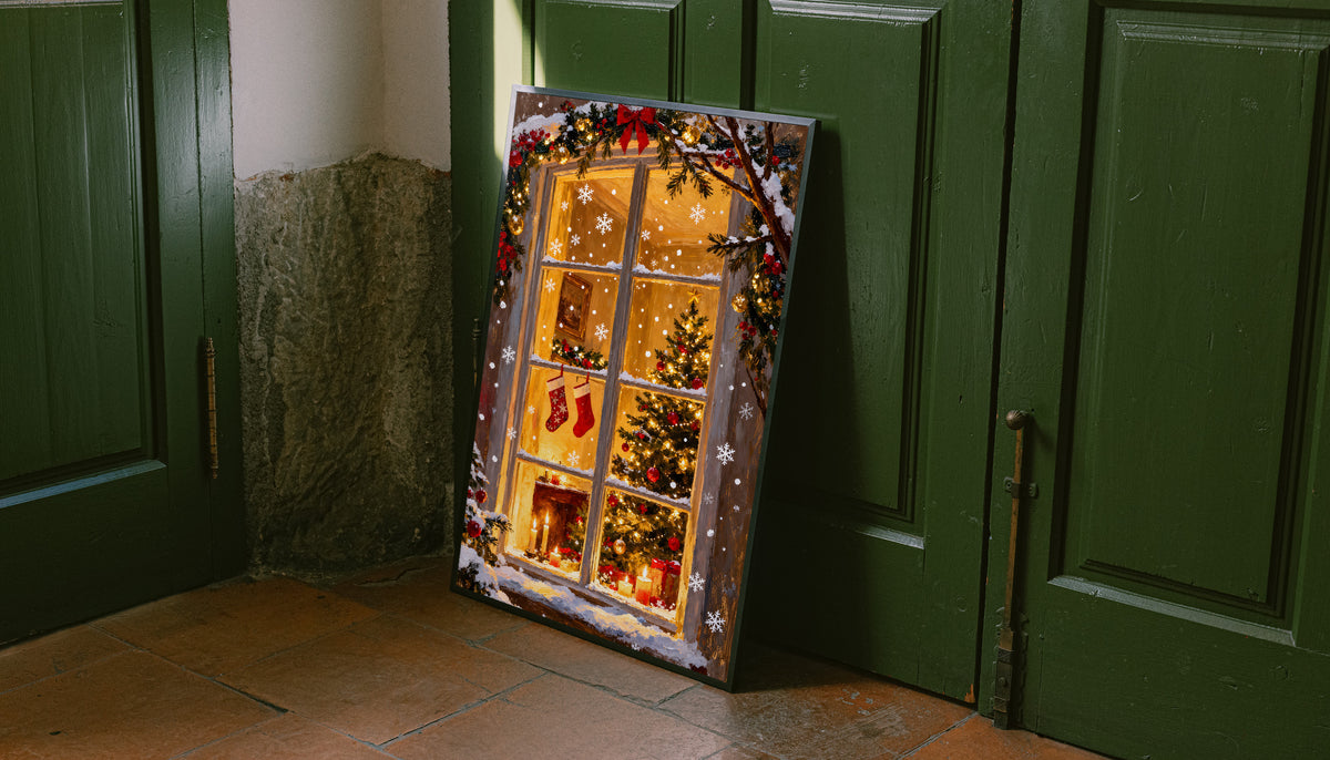 Christmas window art print with stockings, a tree, and fireplace, leaning against a door
