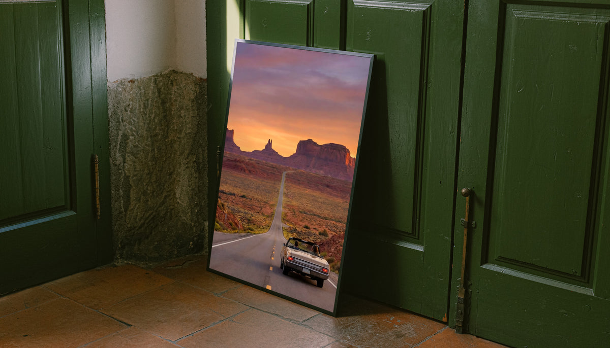 Floor-standing desert road poster with black frame near green doors