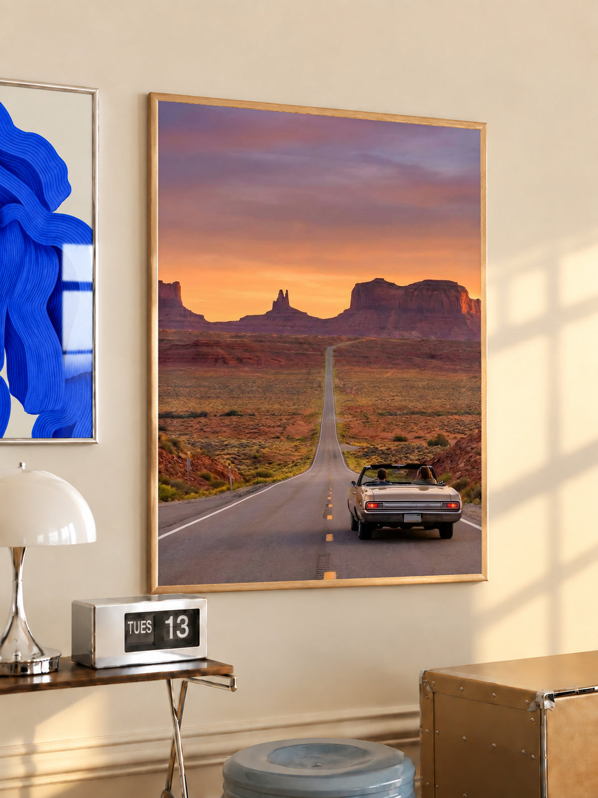 Gold-framed desert road poster with convertible car on straight highway toward mesas