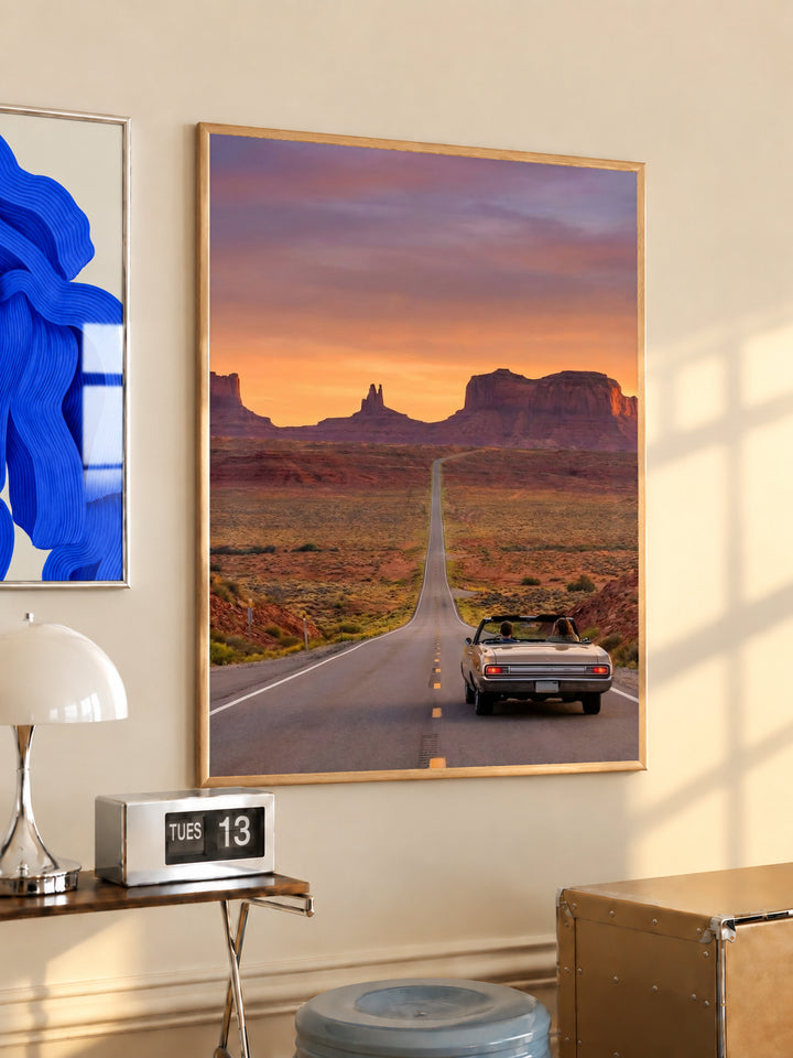 Gold-framed desert road poster with convertible car on straight highway toward mesas