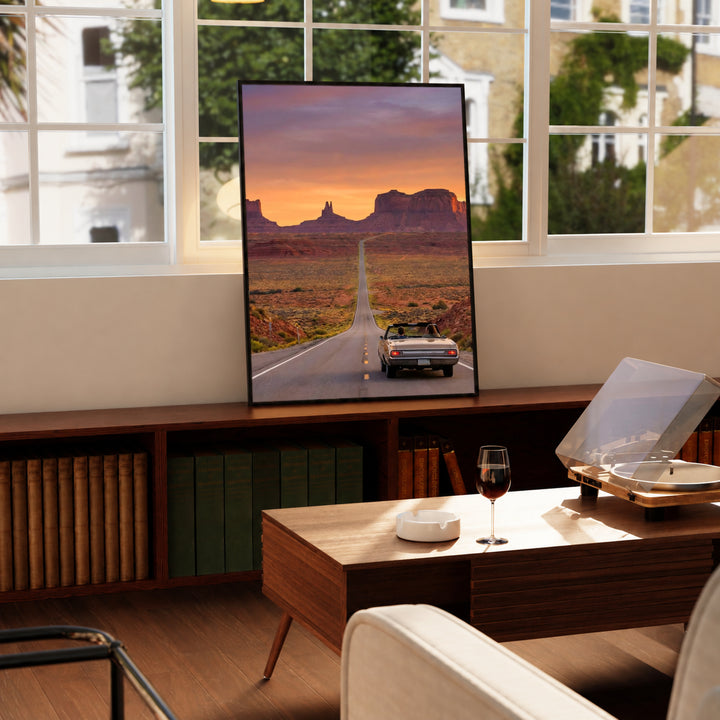 Desk-side desert road poster with black frame showing convertible car at sunset