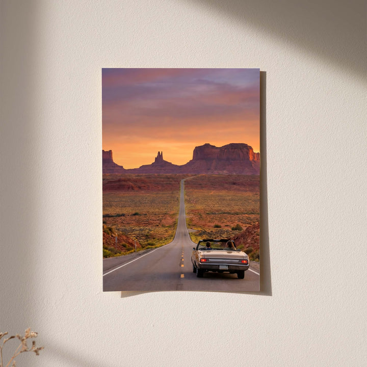 Desert road poster showing convertible car on desert highway at sunset mesas