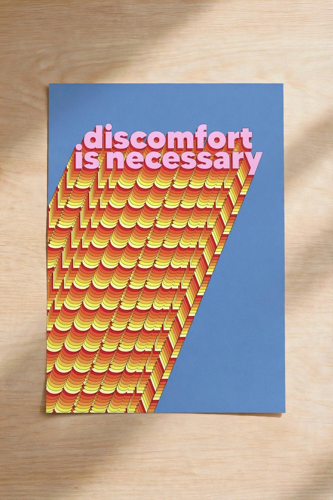 Blue wall art print with colorful wavy stripes and text “discomfort is necessary”