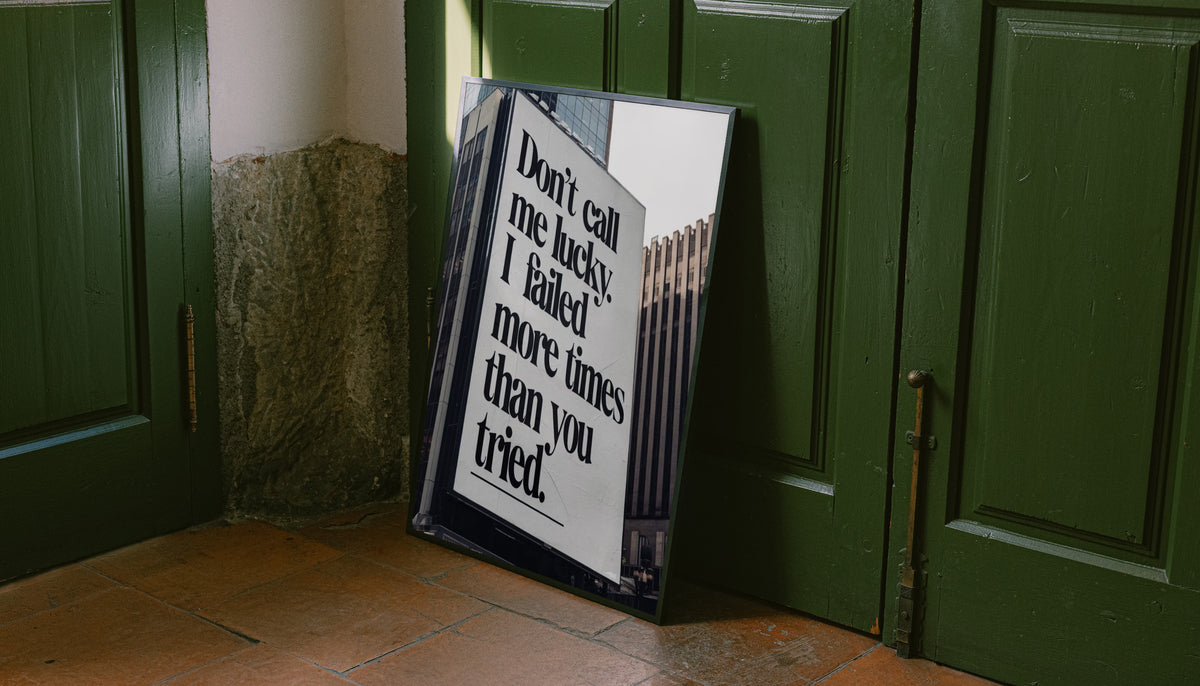 Black-and-white quote poster in dark frame, leaning against green doors