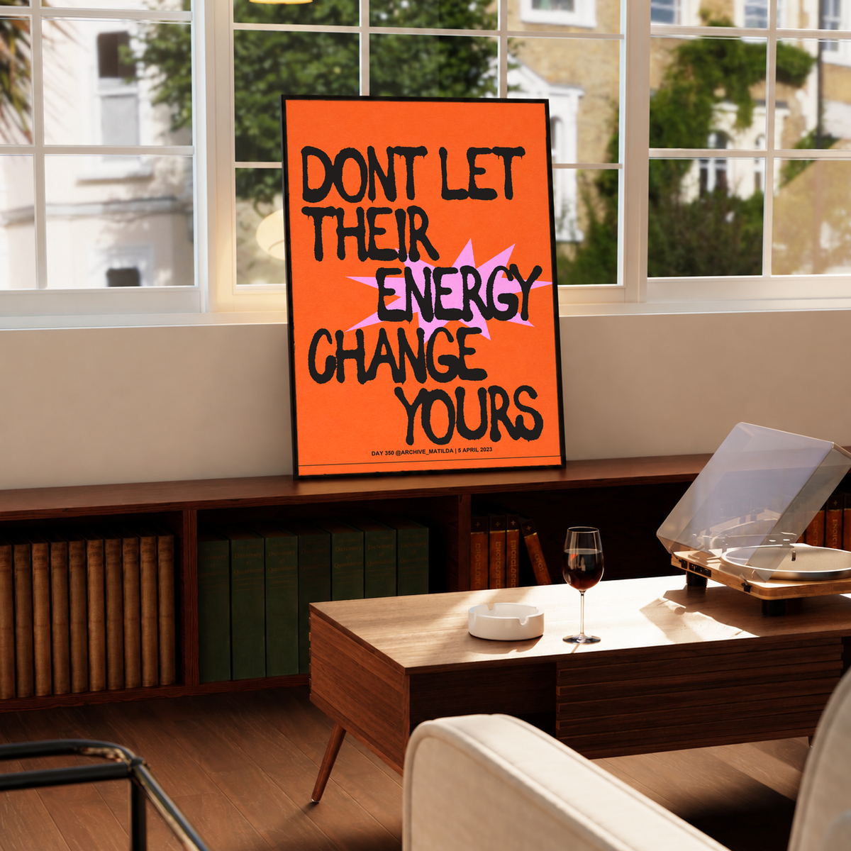 Orange framed poster on a wooden surface, black and pink quote lettering