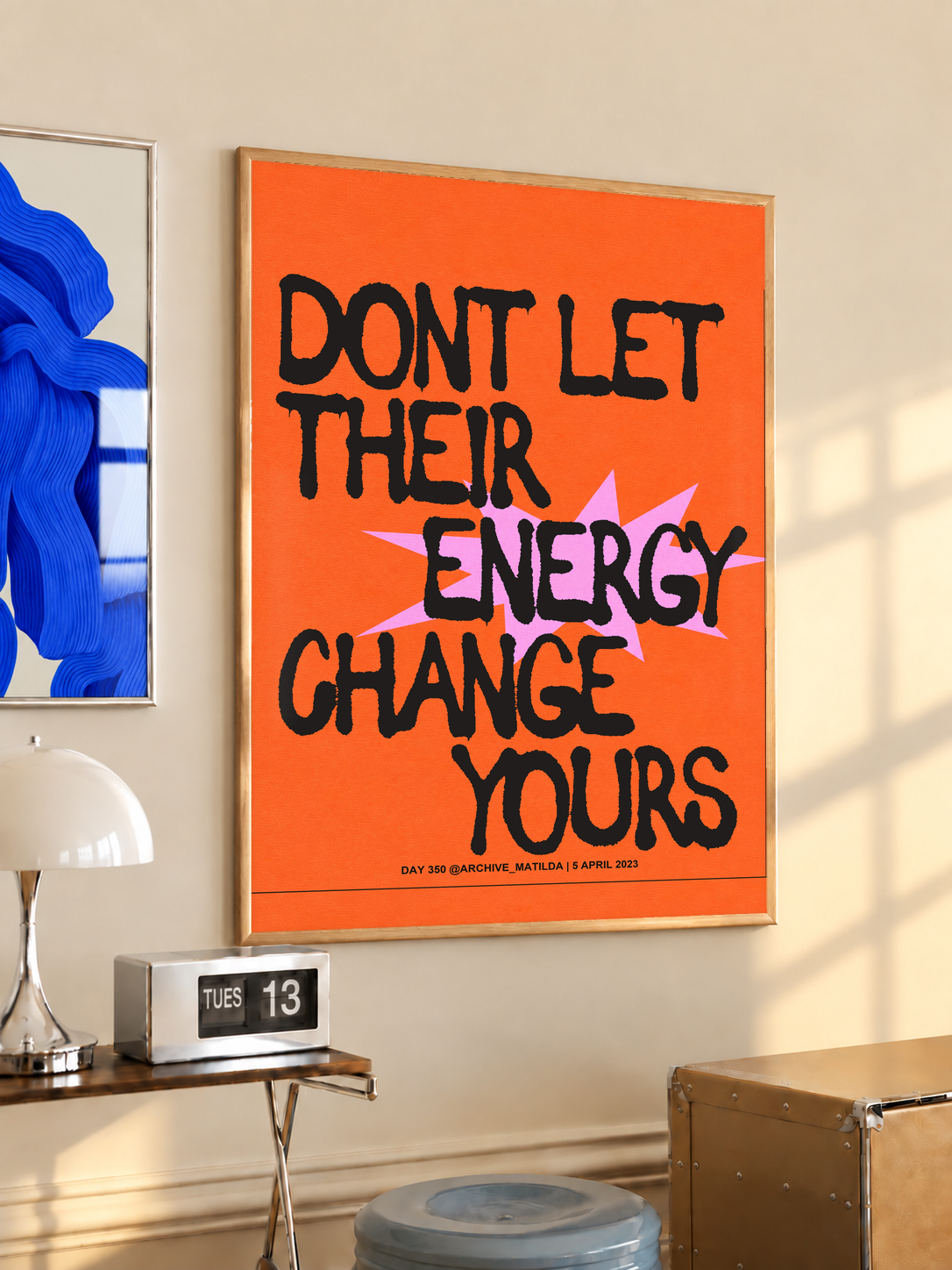 Orange wall poster with black border and typographic quote in black and pink colors