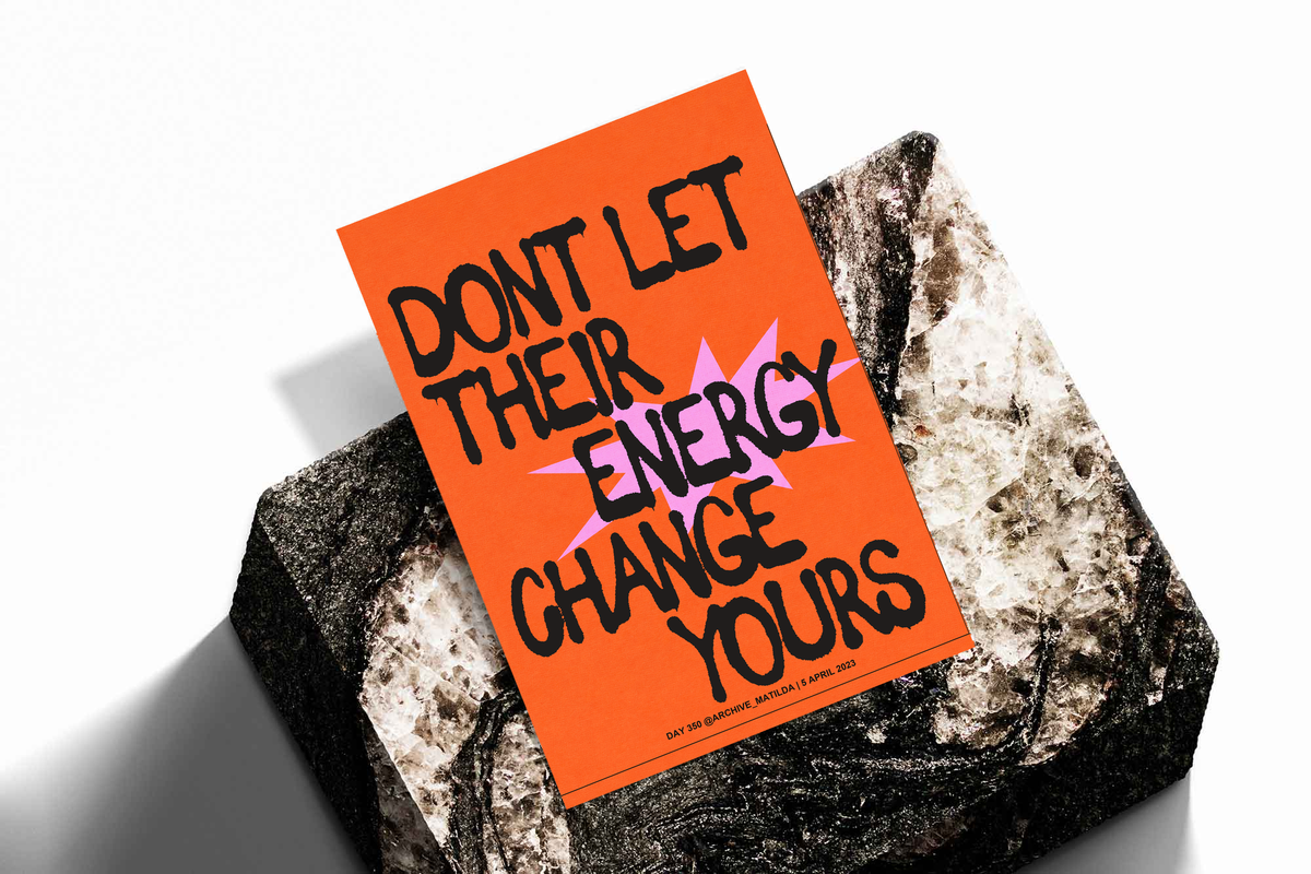 Orange poster with black border on a rock, bold quote lettering in black and pink