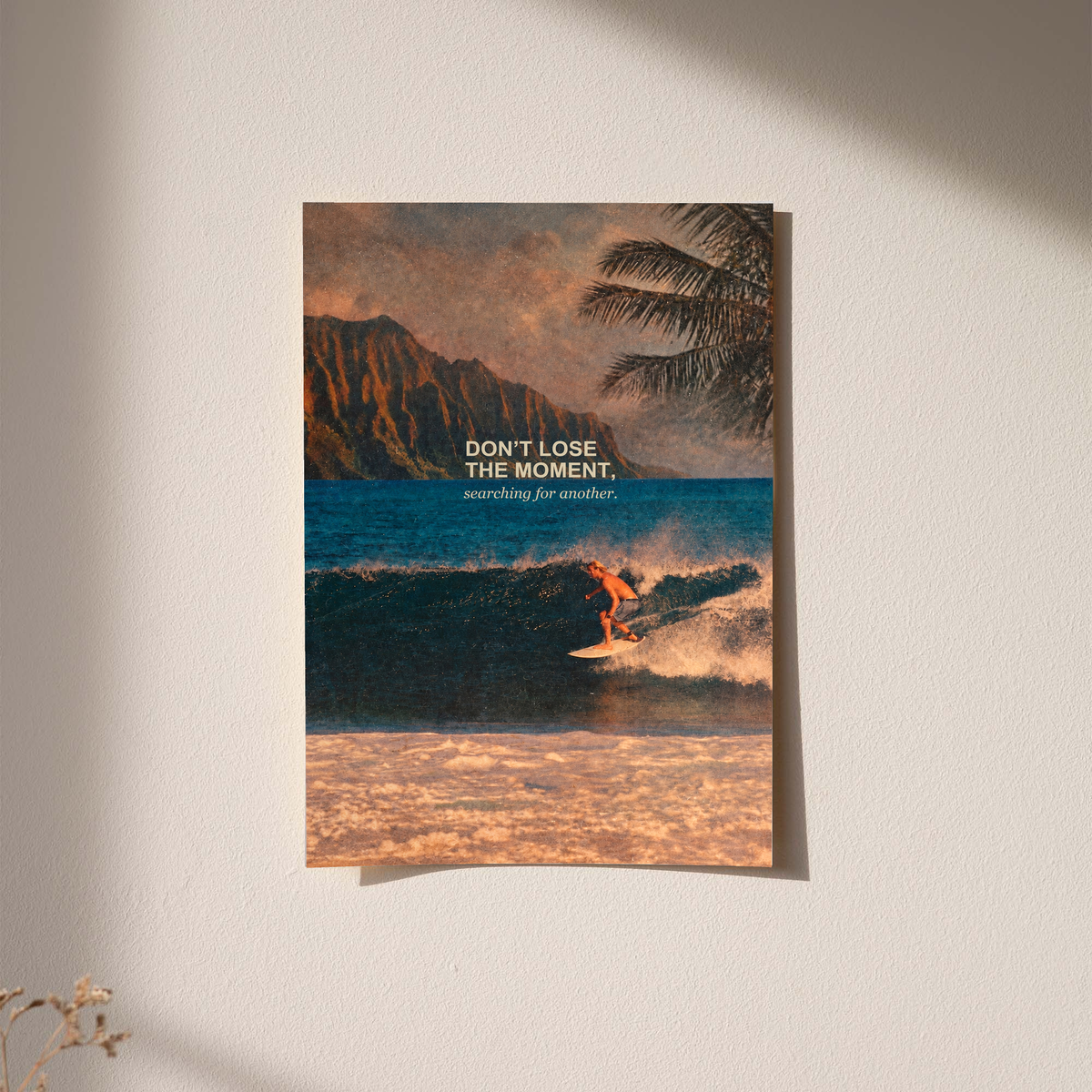 Surfer on a teal wave below warm sunset sky and palm fronds; unframed print on a wall