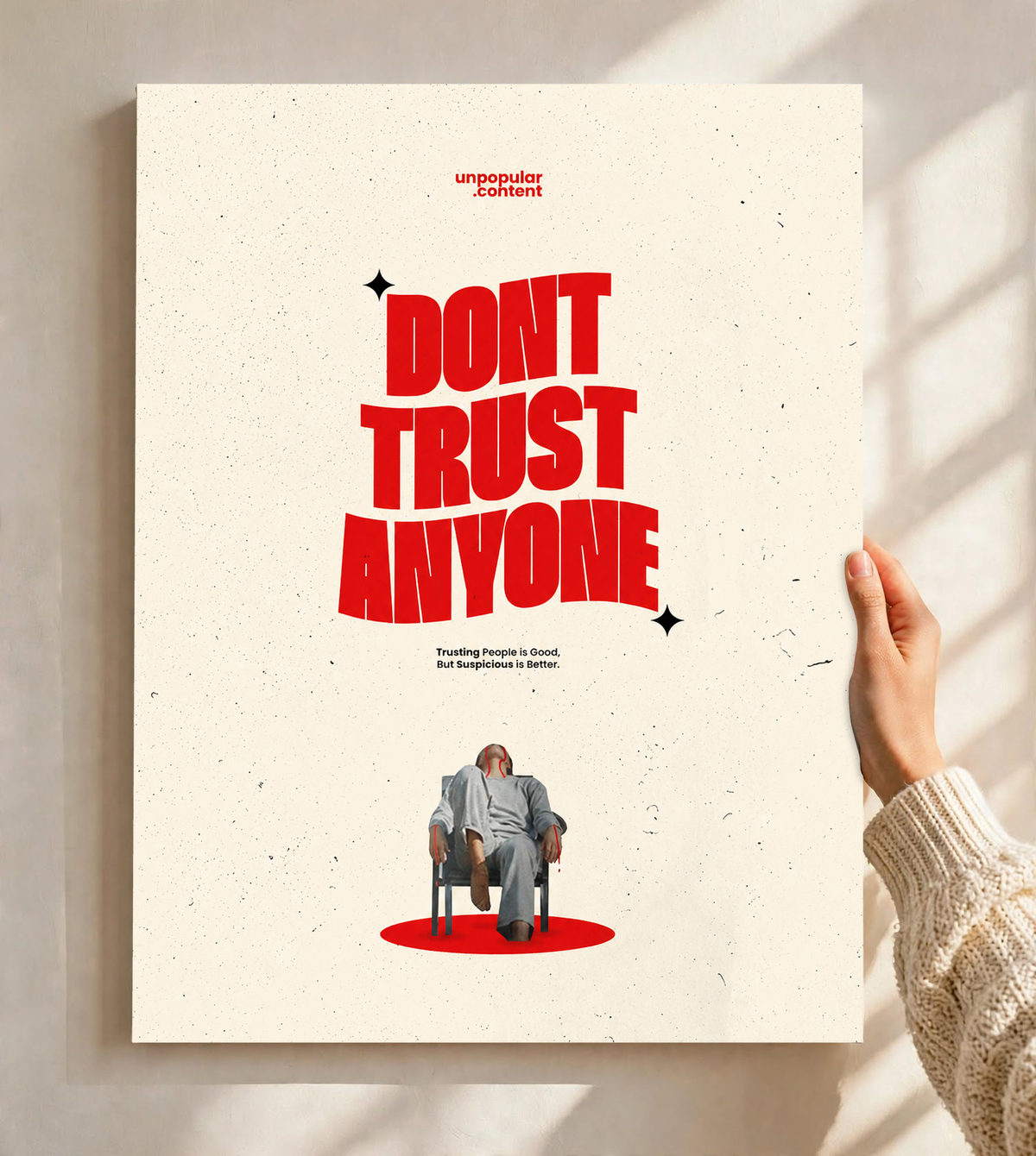 Bold red Don't Trust Anyone typography above a small seated figure on cream as an unframed poster held against a pale sunlit wall