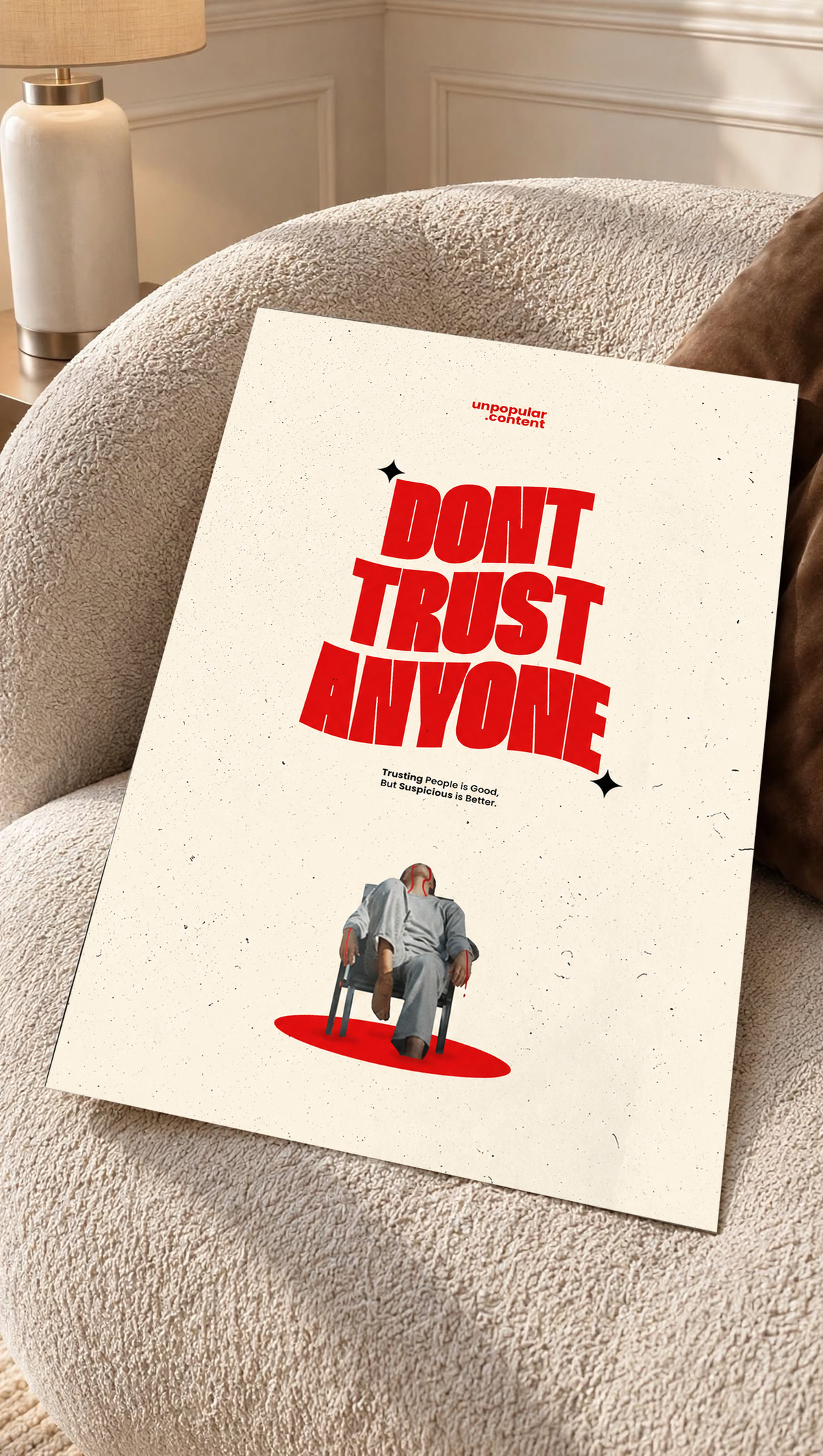 Bold red Don't Trust Anyone typography above a small seated figure on cream as an unframed poster resting on a cream woven chair