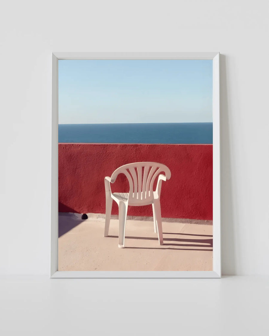 Impresión de silla de playa con marco blanco, pared roja y silla blanca vacía
