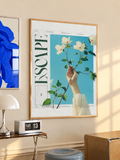 Floral poster in light wood frame, with a hand holding white flowers on a blue background