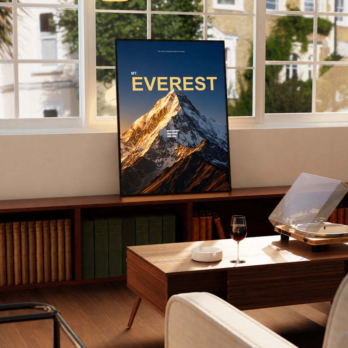 Golden light on a snowy Everest summit with yellow lettering on dark navy; framed print beside a window