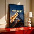 Golden light on a snowy Everest summit with yellow lettering on dark navy; black framed print on a red cabinet