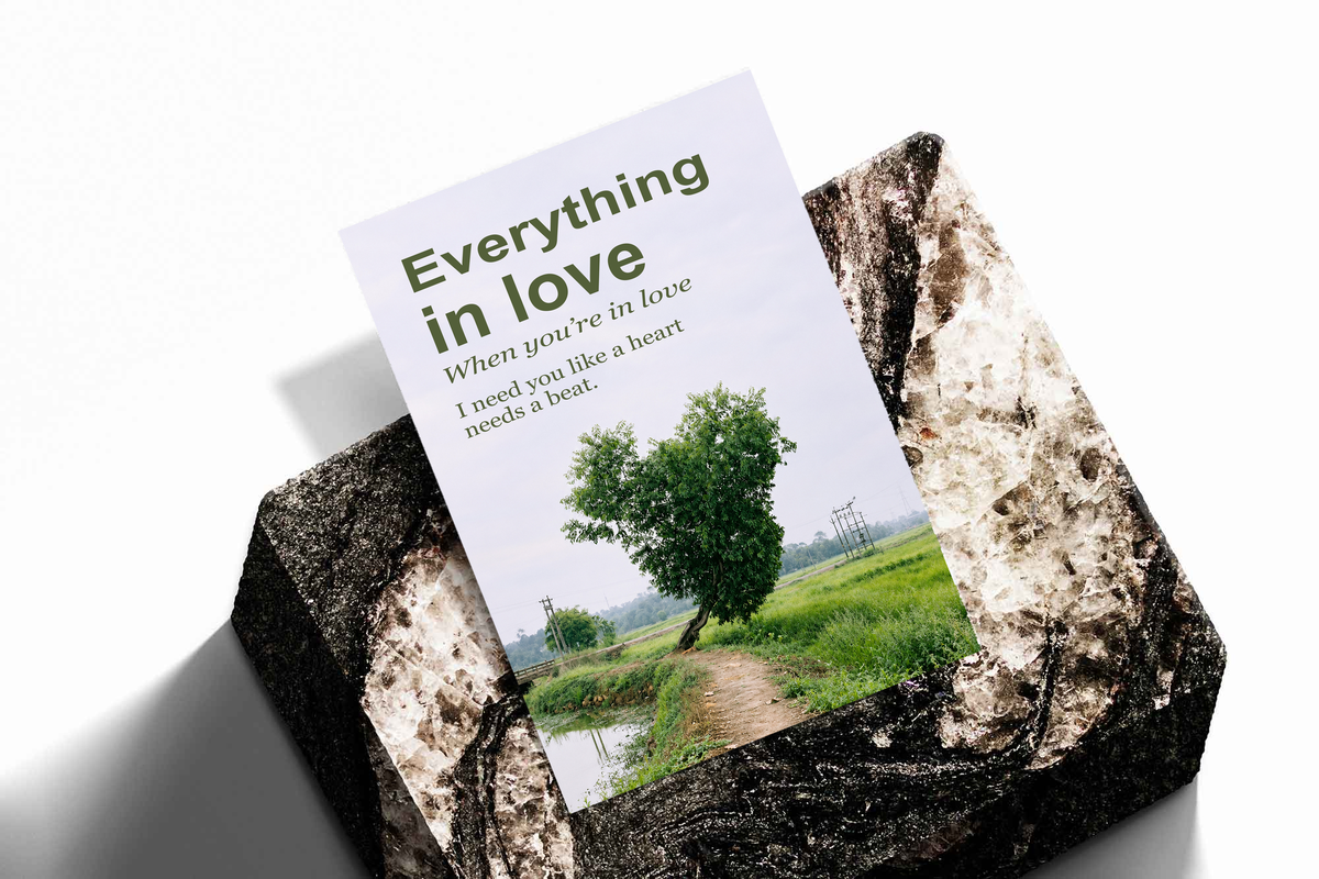 Heart-shaped green tree beside a rural path with Everything in Love lettering; unframed print on a stone display