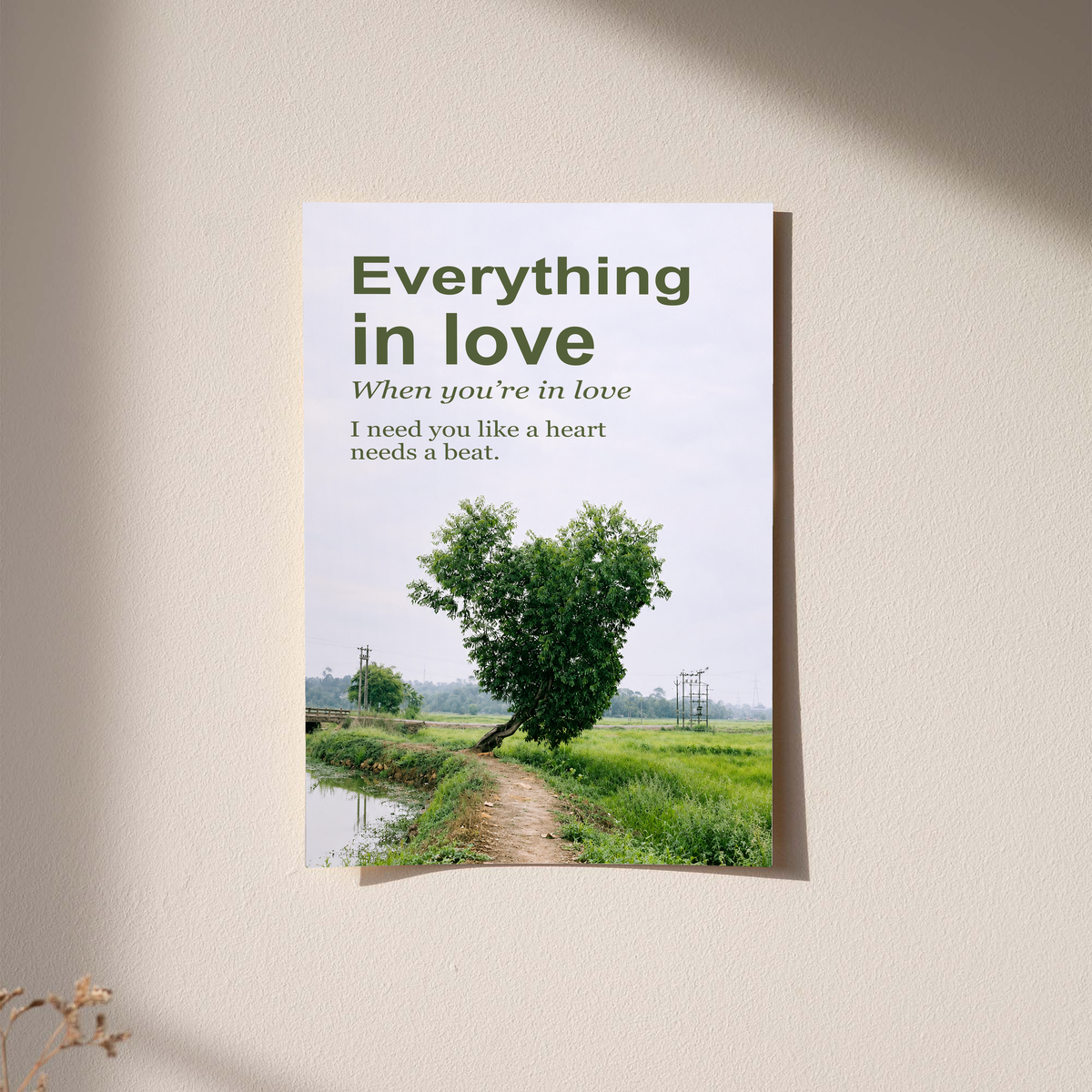 Heart-shaped green tree beside a rural path with Everything in Love lettering; unframed print on a wall