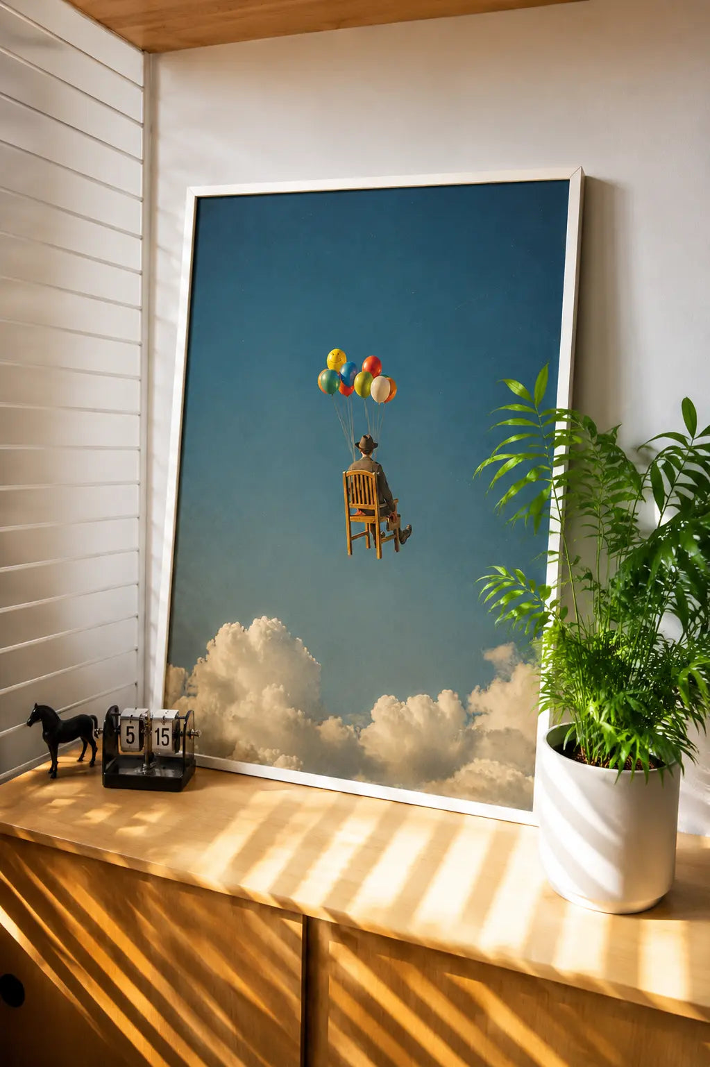 Surreal art print with floating colorful balloons, chair, and clouds in a blue sky