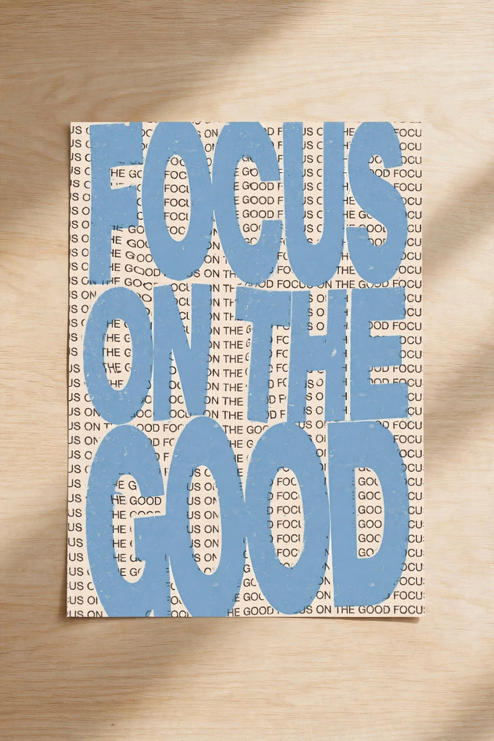 Blue typographic wall print reading “FOCUS ON THE GOOD”