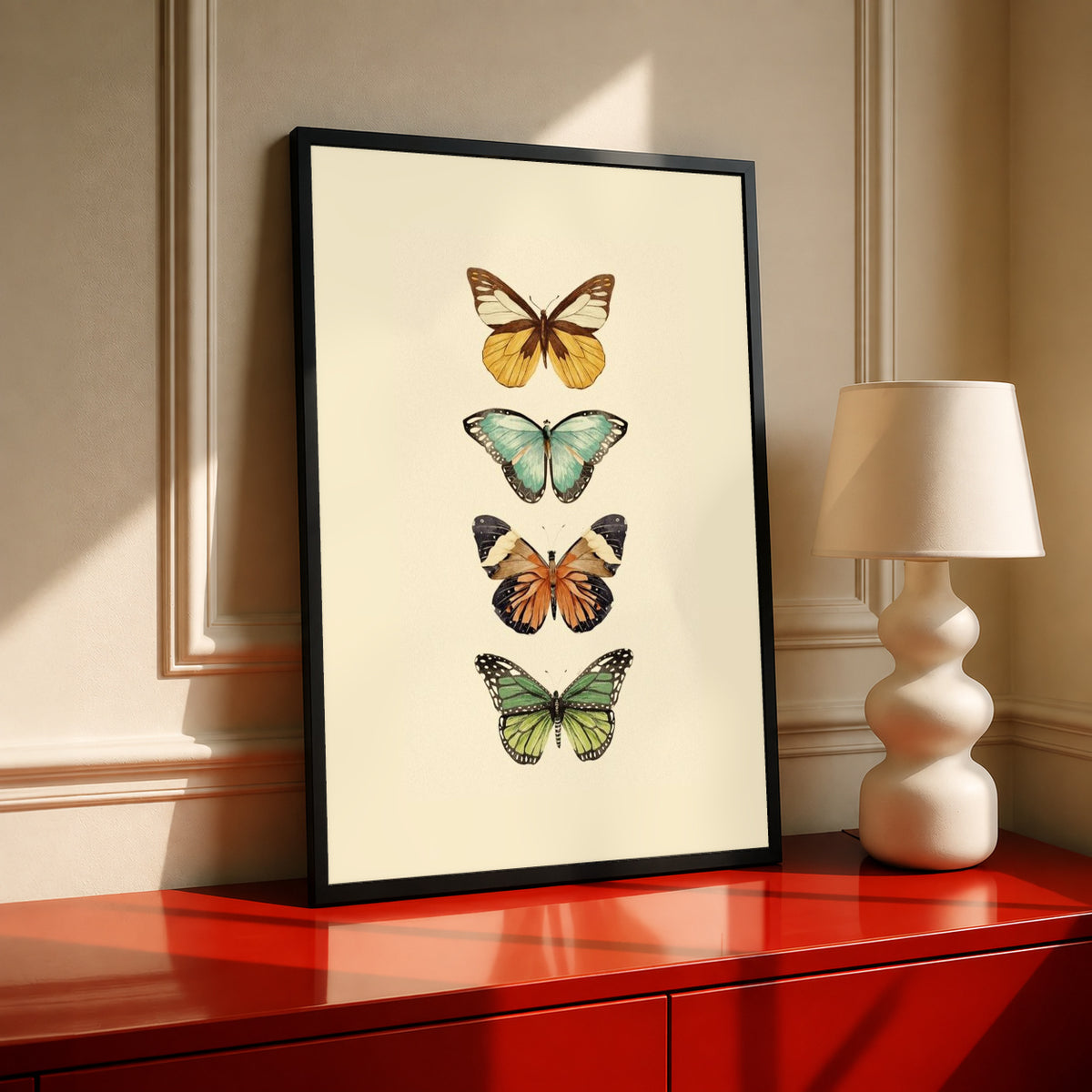 Four-butterfly illustration print in black frame on warm cream background, gold and green tones