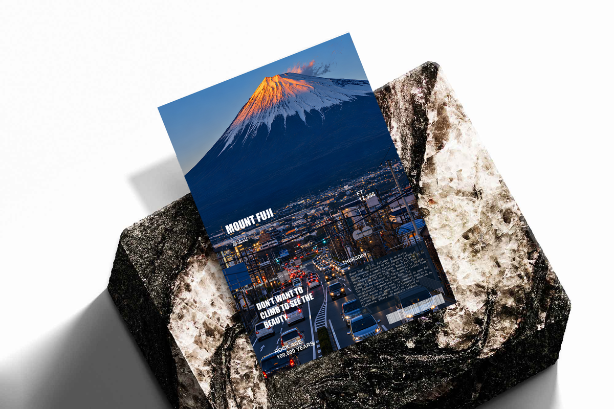 Orange-lit Mount Fuji above a deep blue city in an editorial collage; unframed print on a stone display