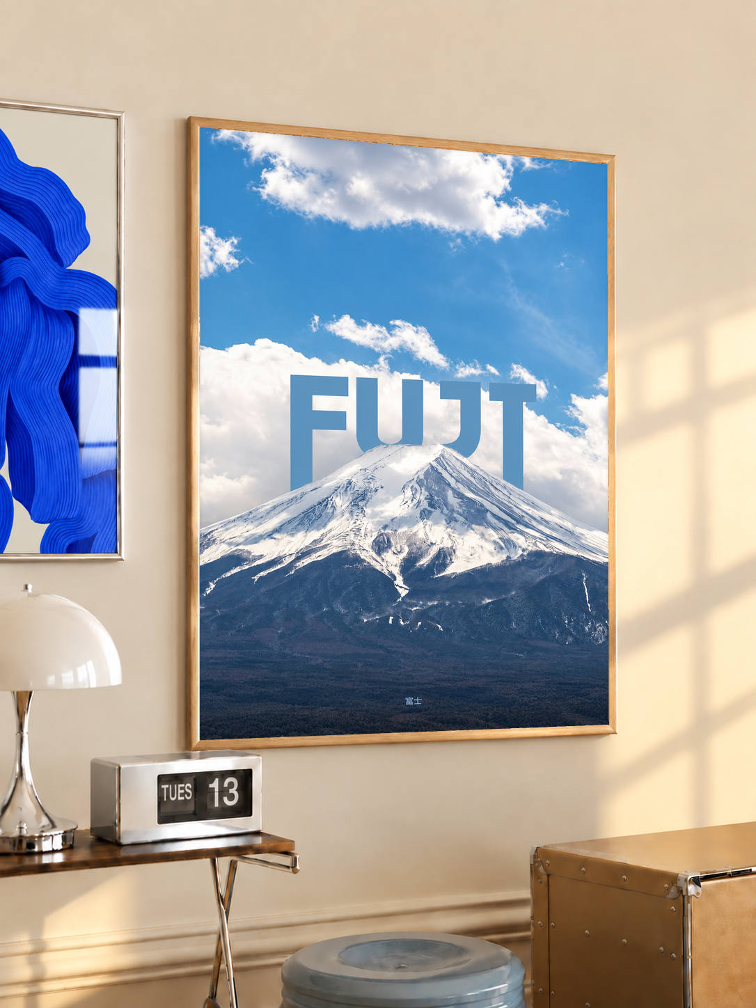 Snow-covered Mount Fuji beneath blue sky and large white FUJI lettering; oak framed print in a desk setting