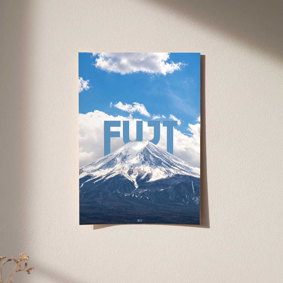 Snow-covered Mount Fuji beneath blue sky and large white FUJI lettering; unframed print on a wall