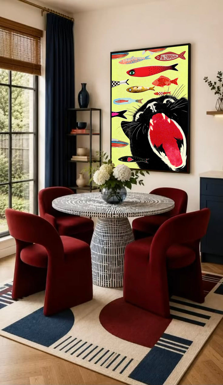 Framed poster on a wall showing a black cat face with red tongue and fish