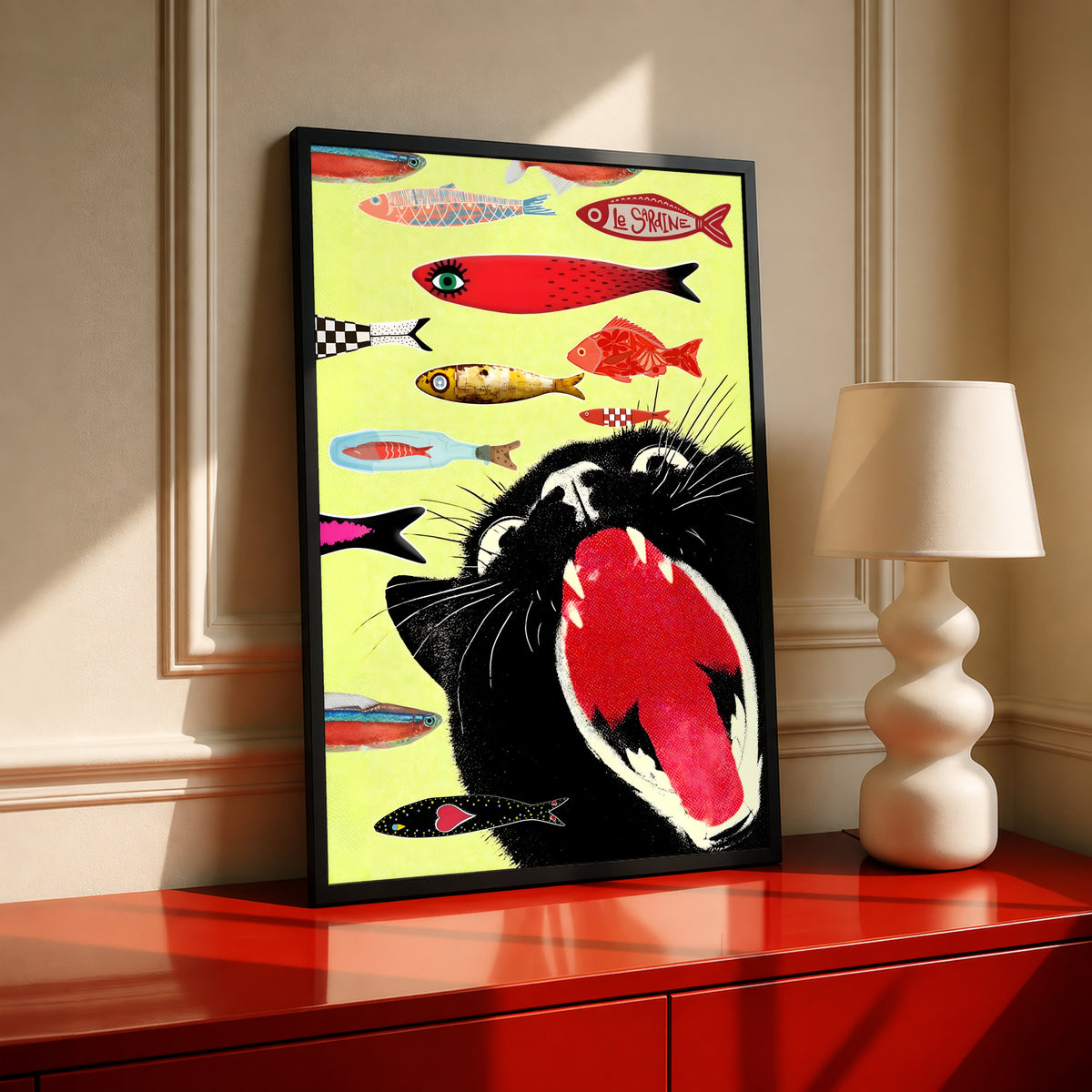Black-framed yellow cat-and-fish poster displayed on a red cabinet