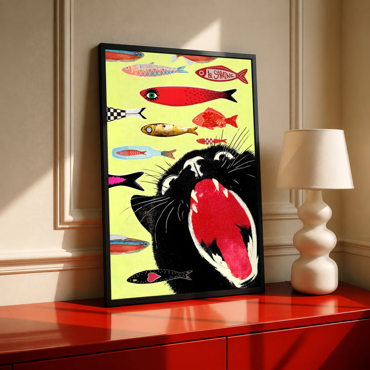 Black-framed yellow cat-and-fish poster displayed on a red cabinet