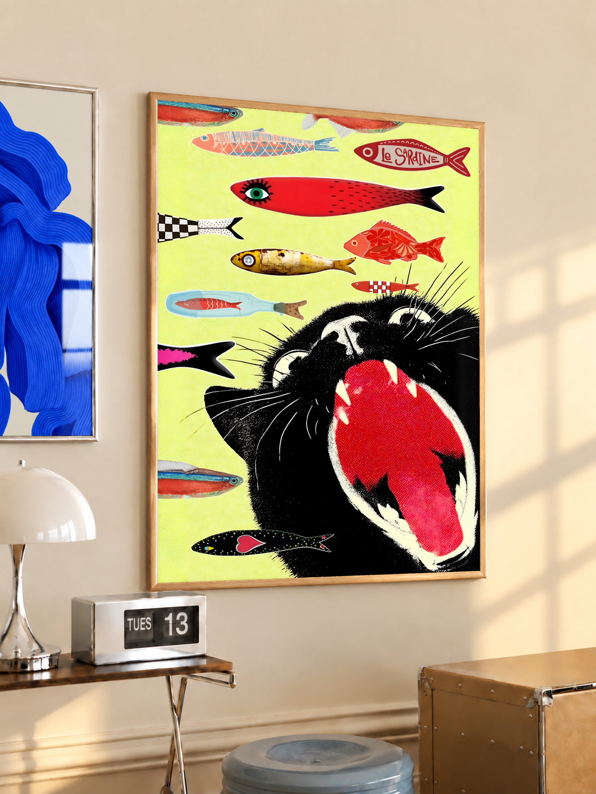 Yellow cat-and-fish art poster leaning on a shelf, framed and front-facing