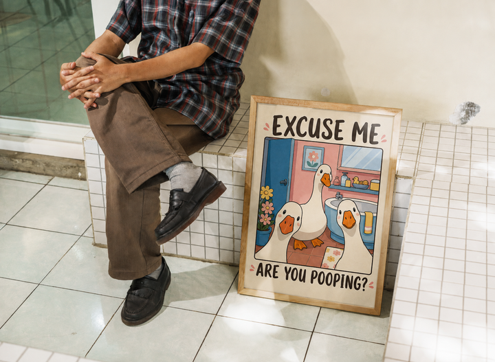 Framed goose wall art print on floor, featuring two geese and 'ARE YOU POOPING?'