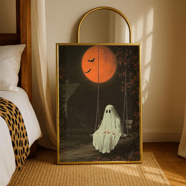 Gold-framed ghost swing art print with orange moon and flying bats, pale ghost figure