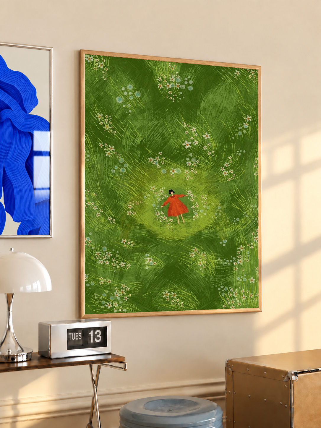 Girl in red dress in a green flower meadow in an oak frame on a warm cream wall above a small table and dome lamp