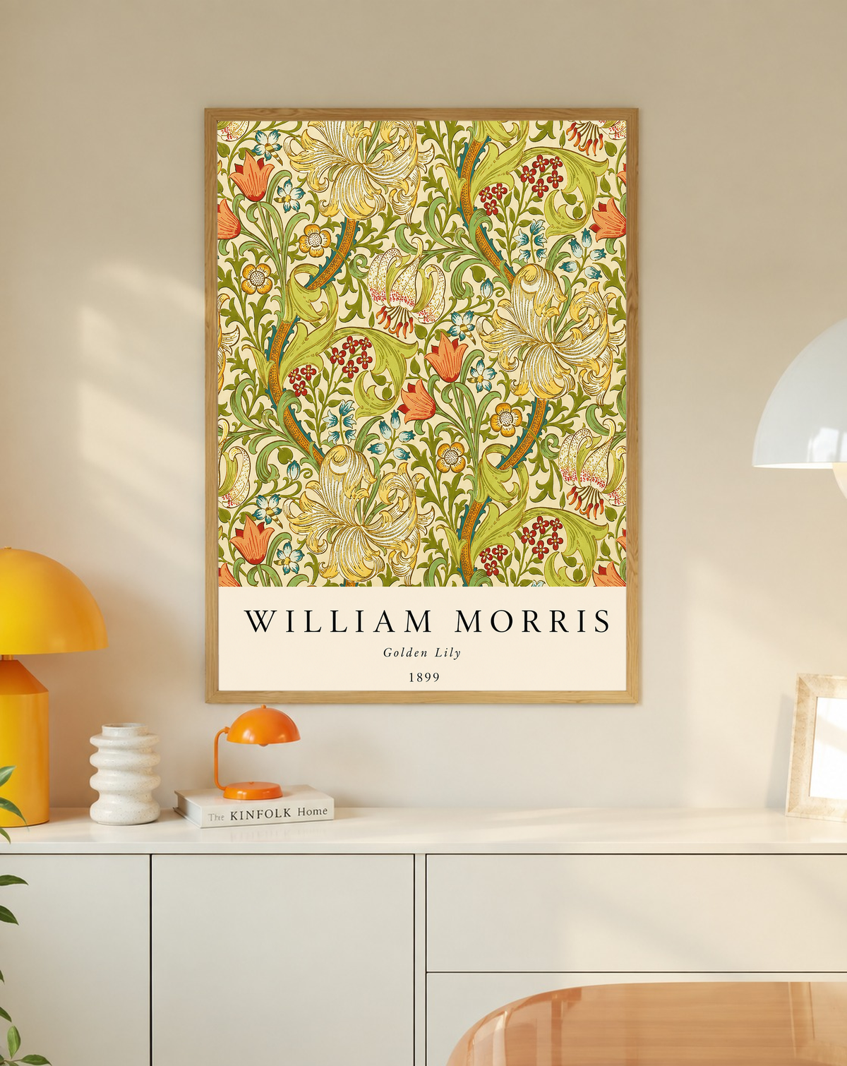 Golden Lily floral pattern with olive leaves, yellow flowers and red accents in an oak frame on a wall above a white cabinet beside a yellow lamp