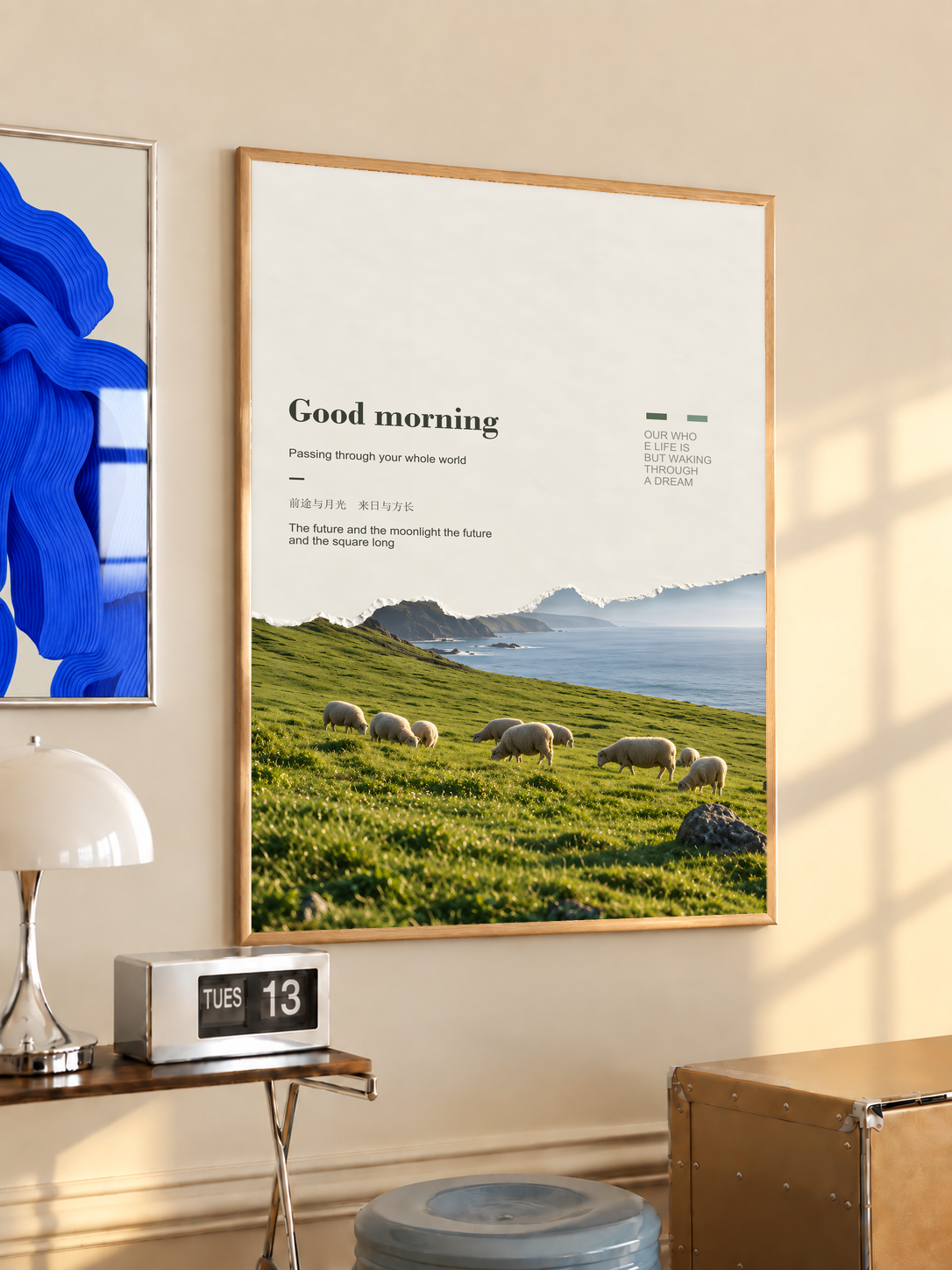 White sheep in a green pasture with misty cliffs and Good Morning lettering; oak framed print in a desk setting