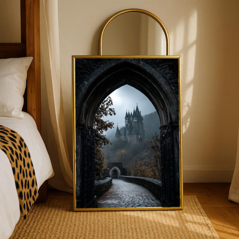 A distant gothic castle seen through a pointed stone arch above a cobbled path in a gold-tone styling frame leaning beside a bedroom mirror