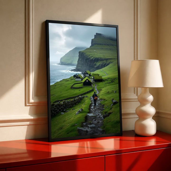 Framed landscape wall art with green cliffs, seaside village houses, and a hiker on path