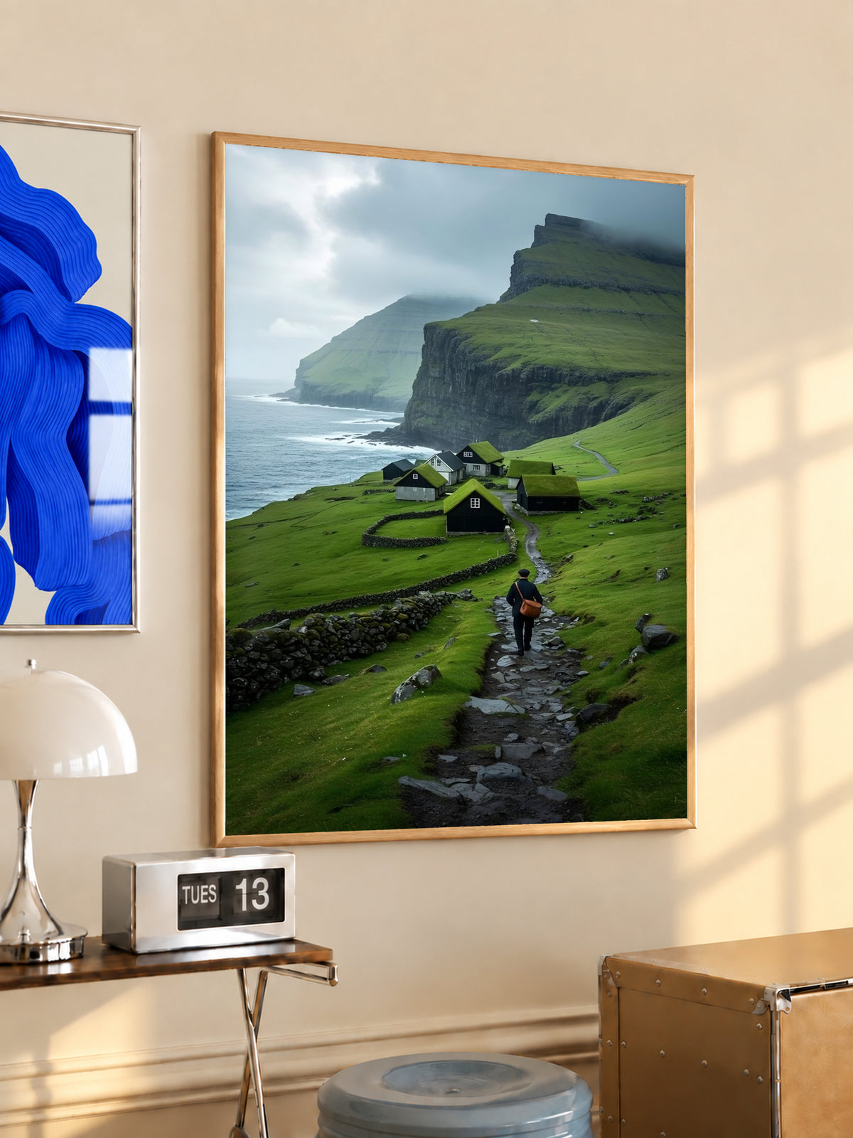 Landscape print in wood frame with green cliffs, sea, village houses, and a hiker