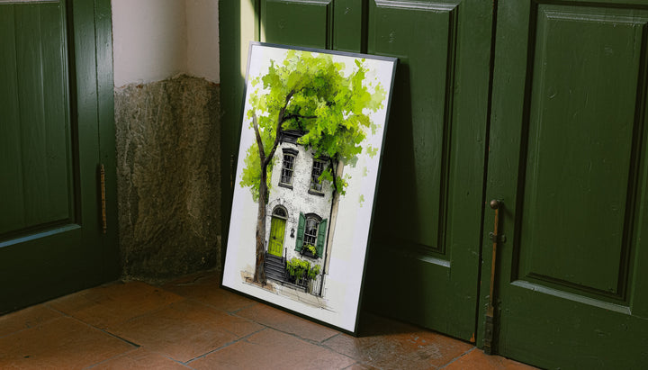 Leaning framed watercolor townhouse print with leafy green tree and green door