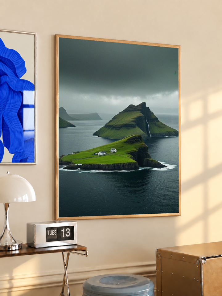 Green island cliffs and dark sea in an oak frame on a warm cream wall above a small table and dome lamp