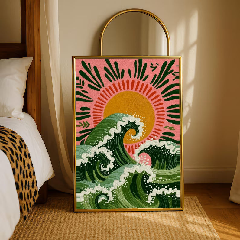 Curling green waves with cream foam beneath an orange sun on a pink background in a gold-tone styling frame leaning beside a bedroom mirror
