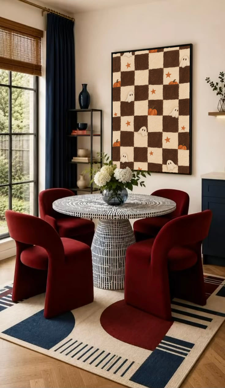 Brown and cream Halloween checkerboard with little white ghosts, pumpkins and orange stars in a black frame on the wall of a dining nook with red chairs