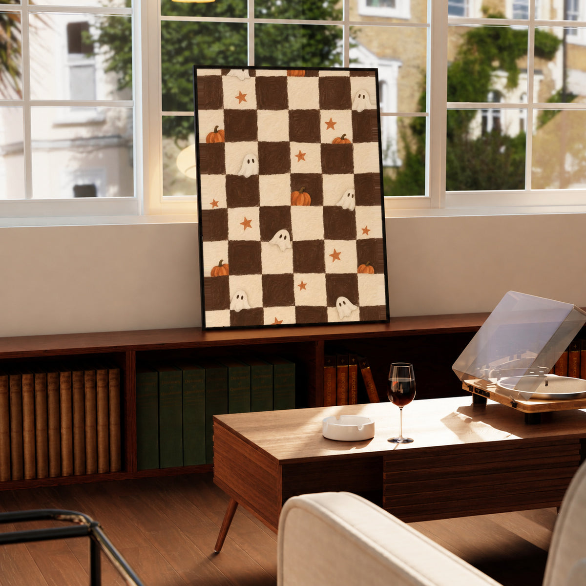 Brown and cream Halloween checkerboard with little white ghosts, pumpkins and orange stars in a black display frame on a wooden console beside a sunlit window