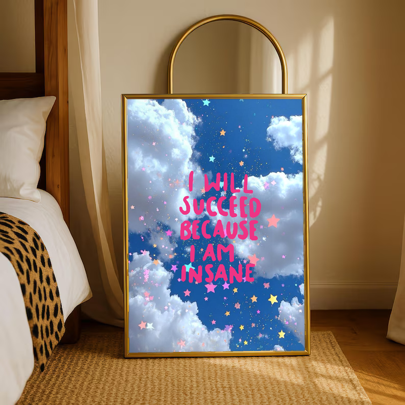 Gold-framed standing poster with blue clouds, star confetti, and pink quote text