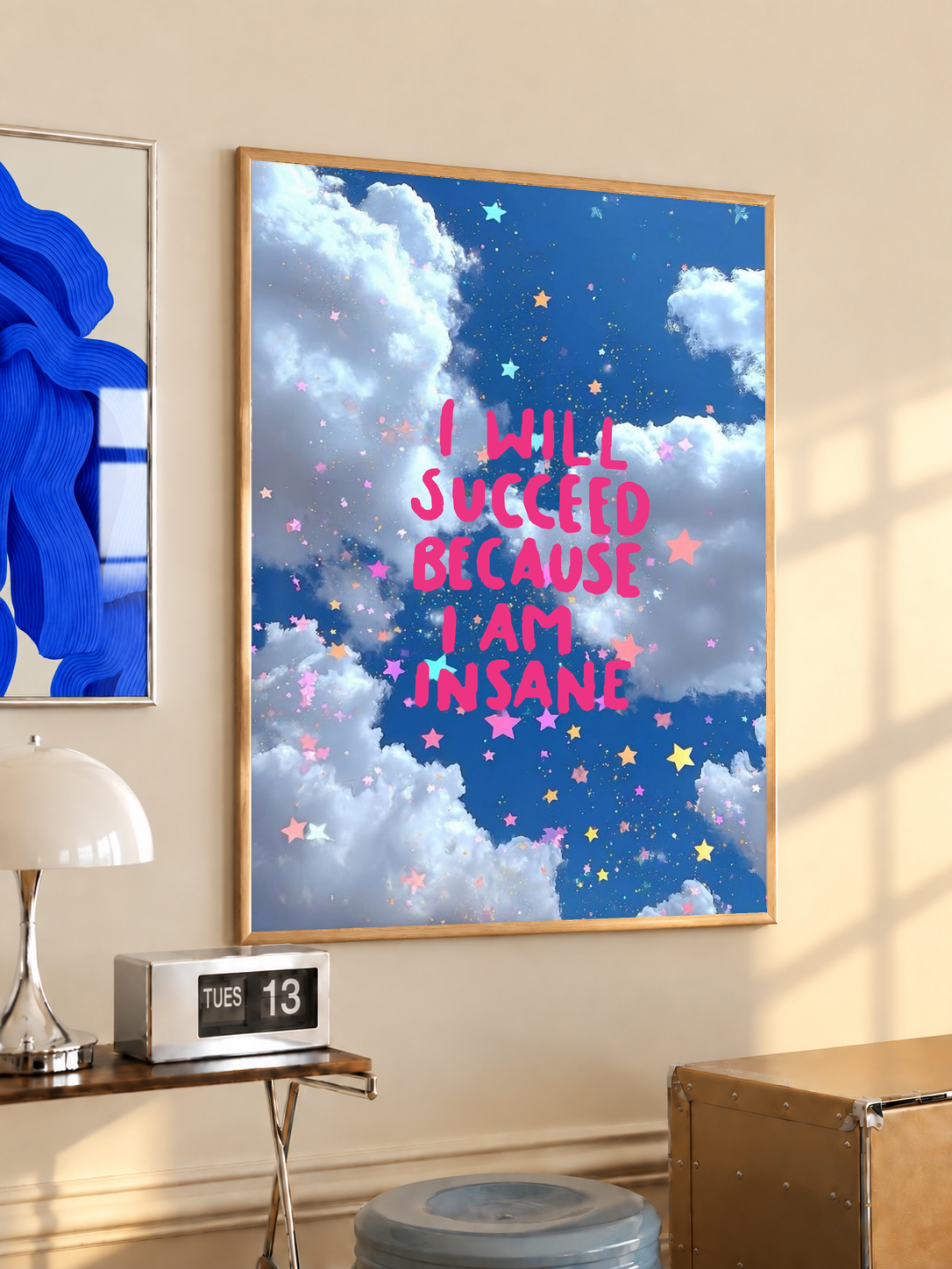 Framed poster on wall with blue clouds, sparkles, and pink quote lettering